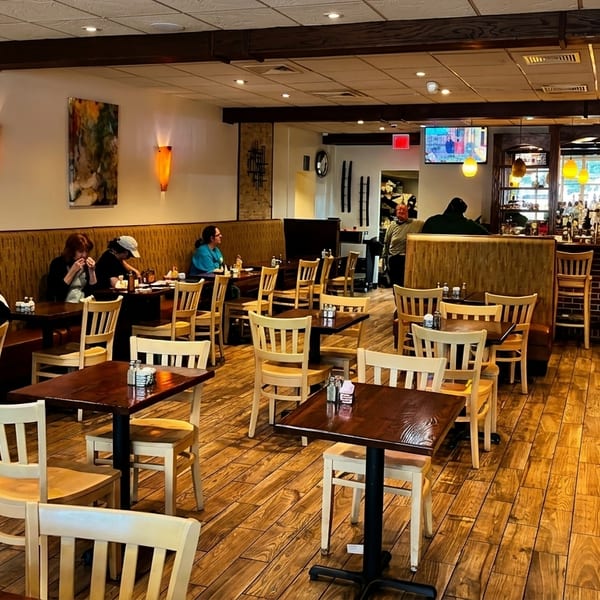 Warmly lit restaurant interior with patrons dining at tables, booths, and a full bar.